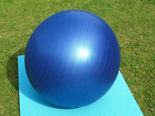 Blauer Gymnastikball auf grünem Rasen